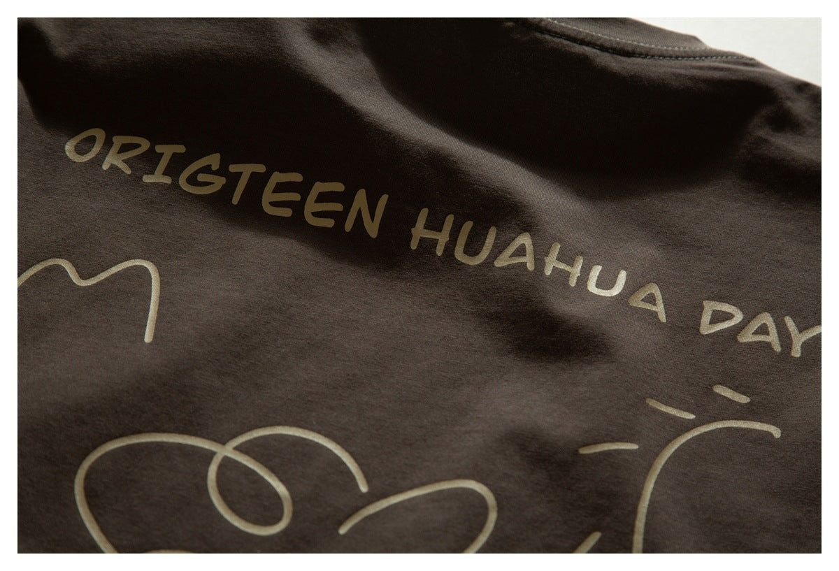 Close-up of a tan printed design with ORIGTEEN HUAHUA DAY lettering on dark brown fabric.