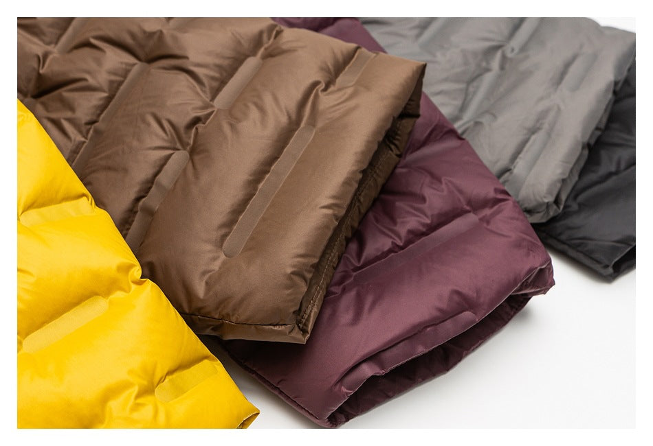 Close-up of folded quilted puffer jackets in yellow, brown, plum, gray, and black.