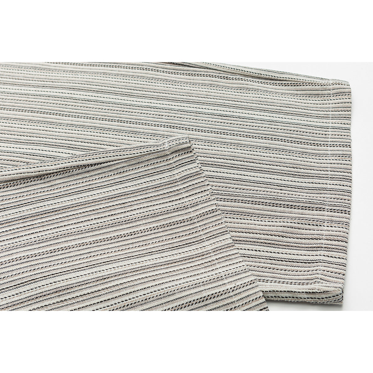 Close-up of cream trousers with fine black stripes, showing a folded leg and stitched edge.