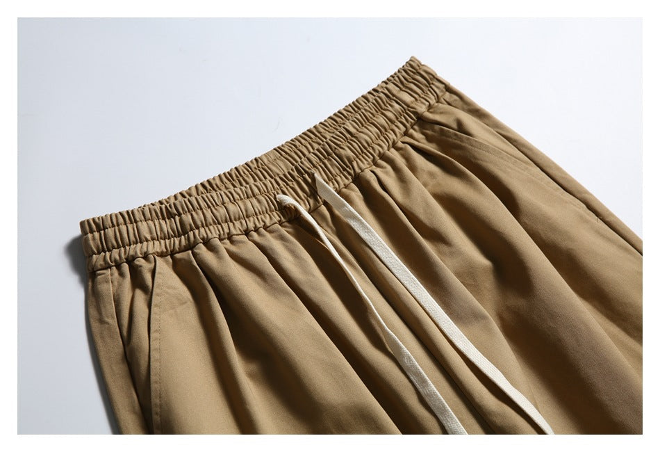 Close-up of tan trousers showing the gathered elastic waistband and long white drawstrings.