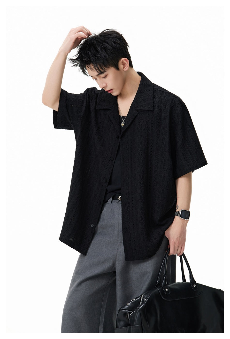 Model wearing a black short-sleeve button-up shirt with a textured openwork pattern and wide collar.