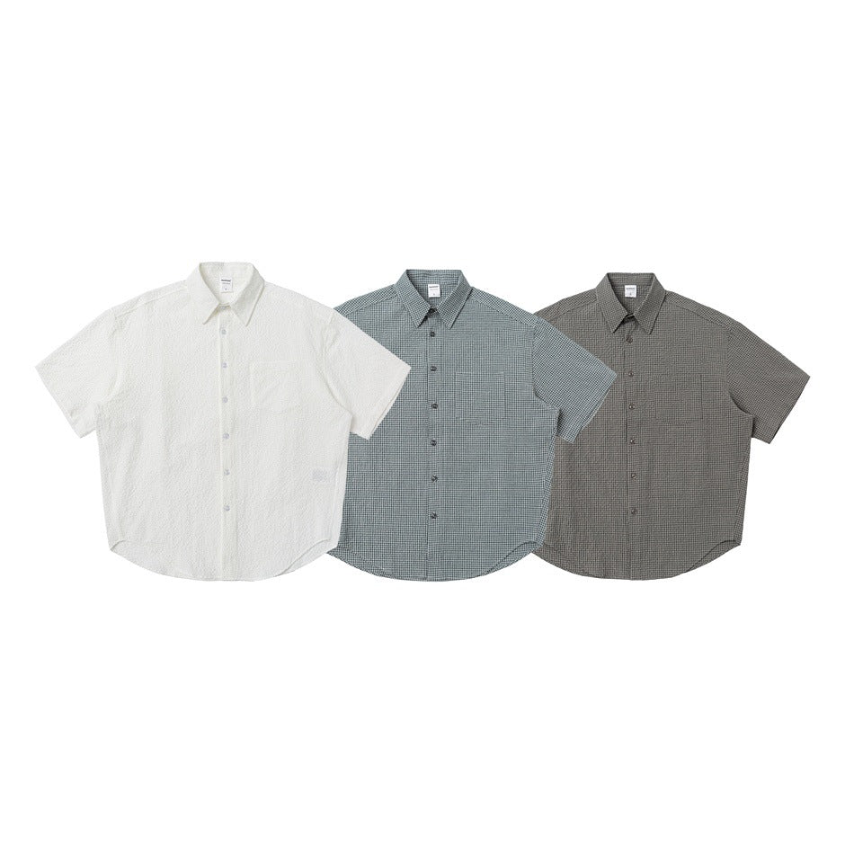 Three short-sleeve button-up shirts shown from the front in white, gray check, and charcoal check.