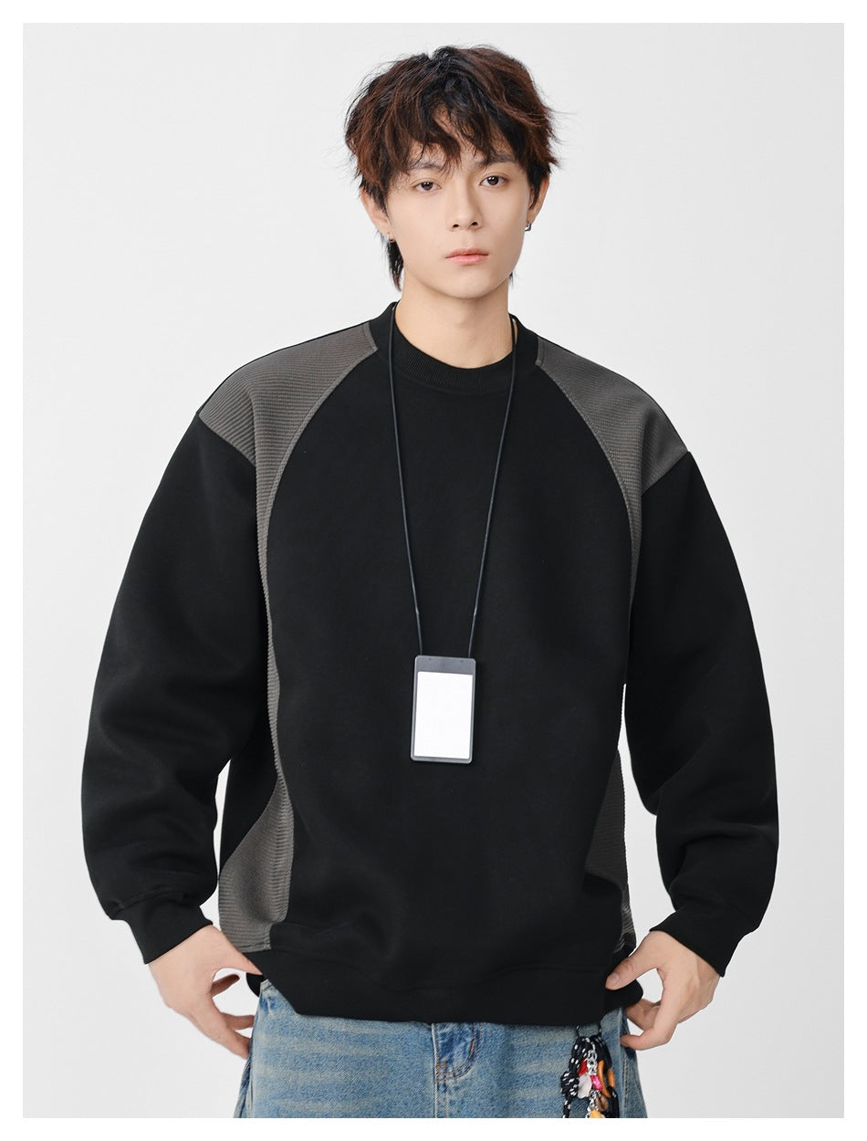 Front view of a model wearing a black crewneck sweatshirt with charcoal shoulder and side panels.