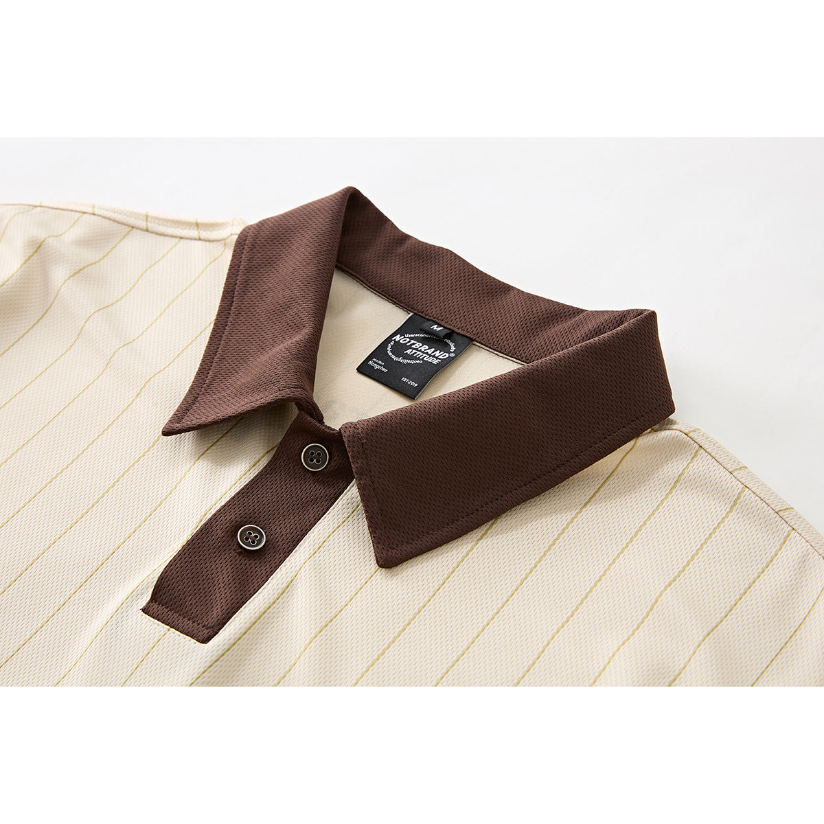 Close-up of a cream pinstriped polo shirt with a dark brown collar, placket, buttons, and neck label.