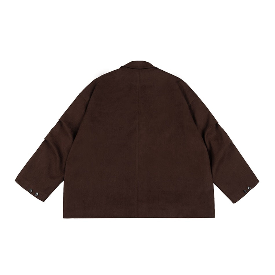 Back view of a dark brown oversized blazer with a center seam, broad sleeves, and buttoned cuffs on white.