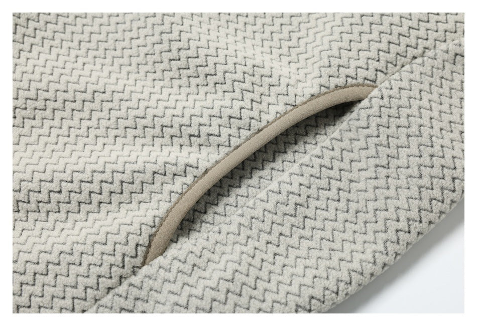 Close-up of a curved pocket opening with beige trim on cream and gray zigzag-patterned fabric.