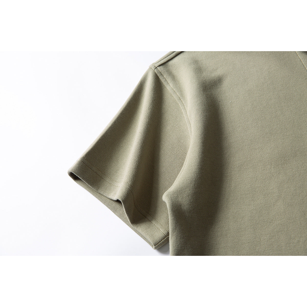 Close-up of a khaki short sleeve and shoulder seam on a collared shirt.