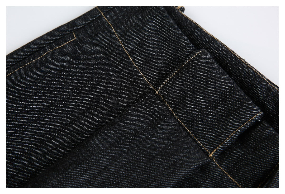 Close-up of black denim jeans showing a pocket edge and tan contrast stitching.
