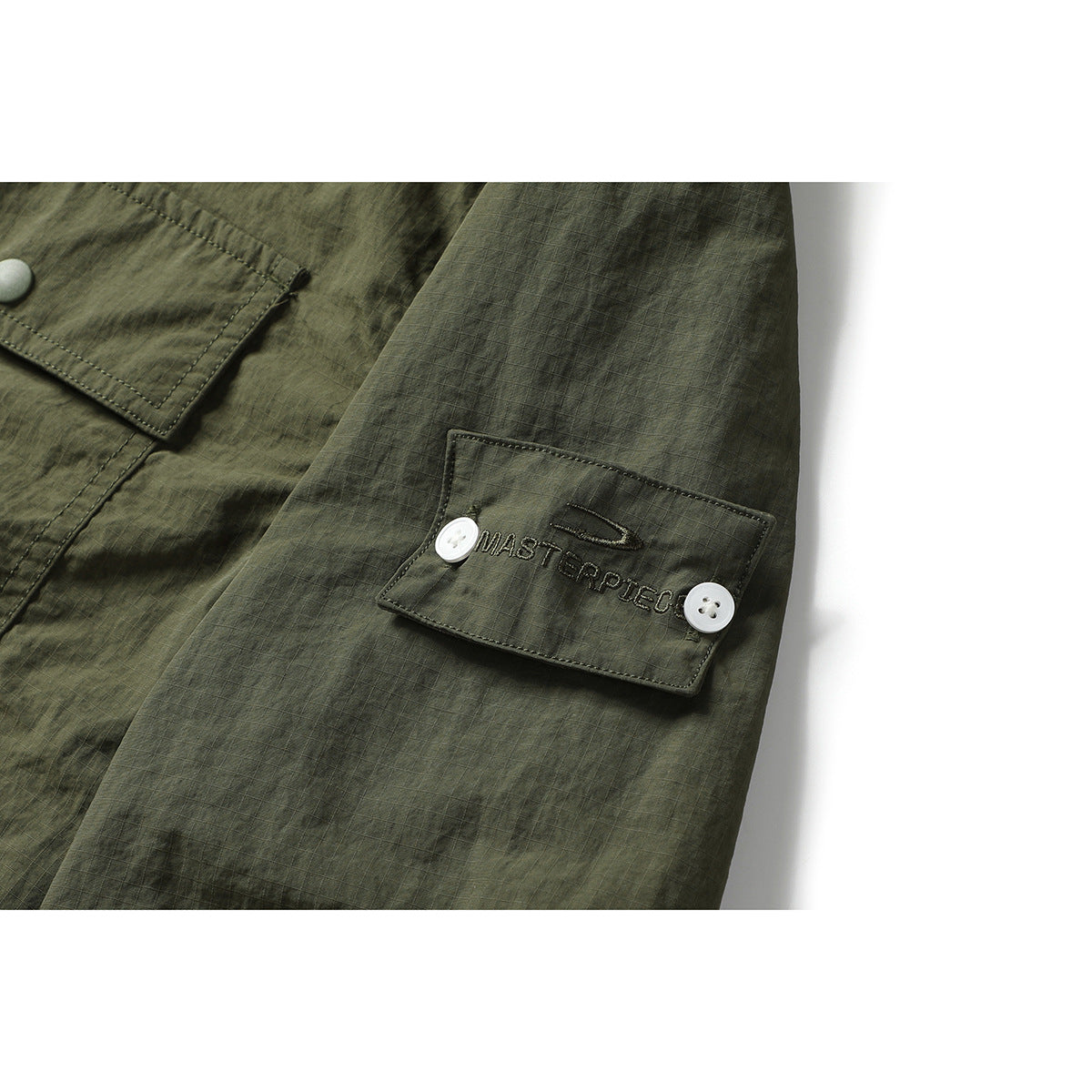 Close-up of an olive-green sleeve tab with white buttons and embroidered lettering.