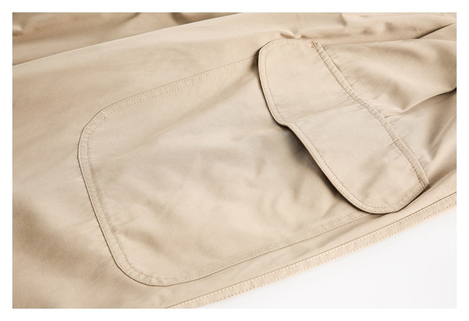 Close-up of a beige trouser pocket with a matching buttoned flap and visible stitching.