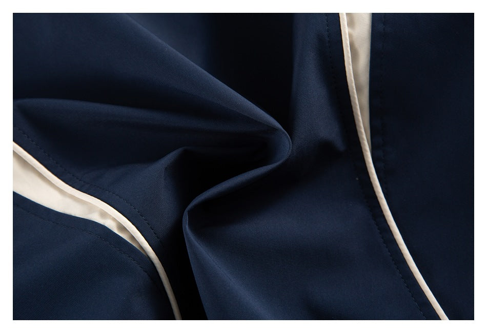 Close-up of navy garment fabric with ivory piping along the seams.