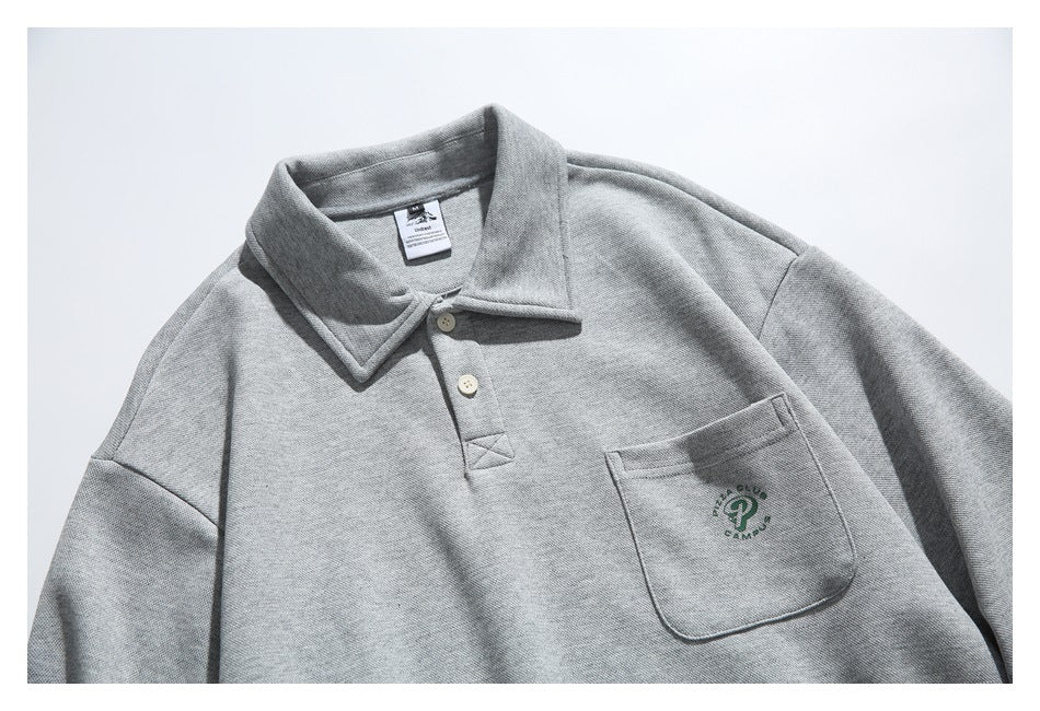 Upper front of a heather-gray collared pullover with a two-button placket and a chest pocket with green embroidery.