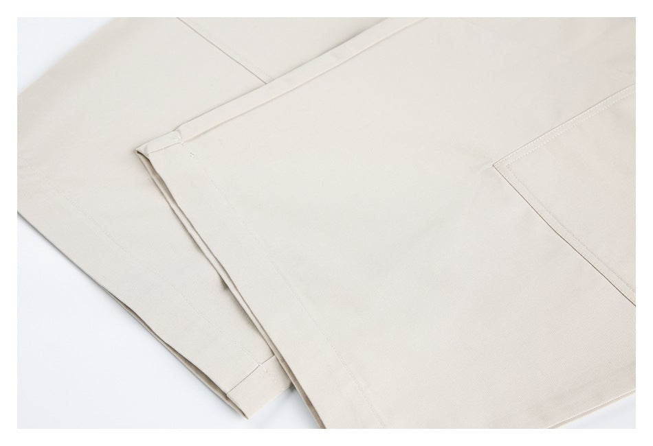 Close-up of folded light beige pants showing a stitched pocket and finished leg hem.