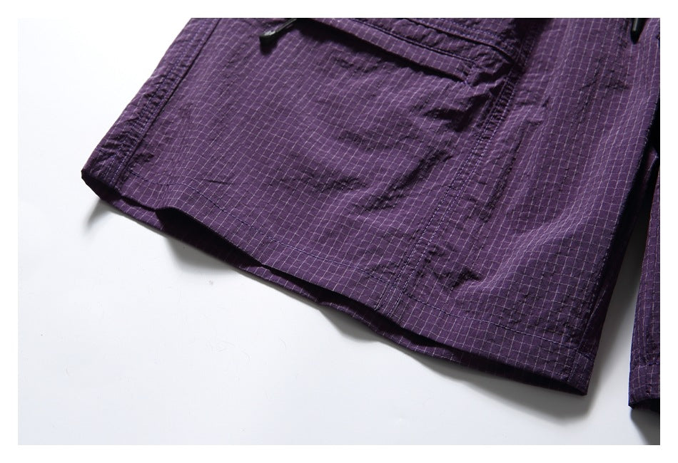 Close-up of a purple shorts leg hem and flap cargo pocket, showing the patterned fabric and stitching.