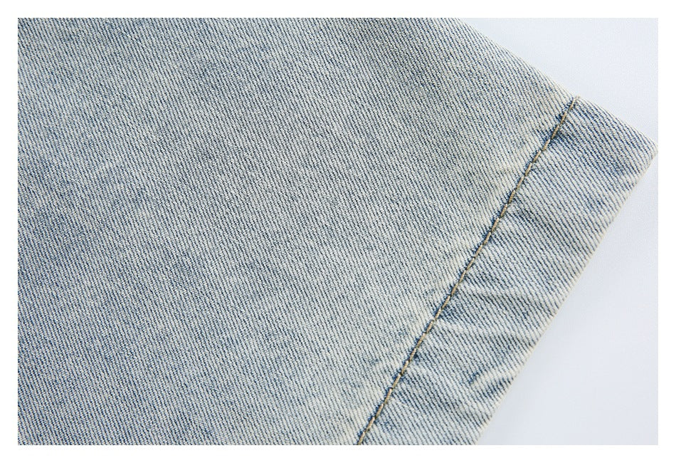 Close-up of light-wash denim with a tan-stitched edge seam.
