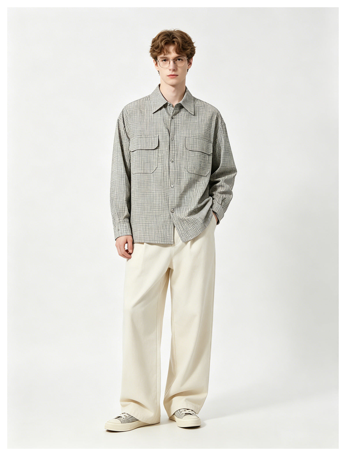 Model wearing a gray check long-sleeve shirt with two flap chest pockets, cream wide-leg pants and sneakers, front view