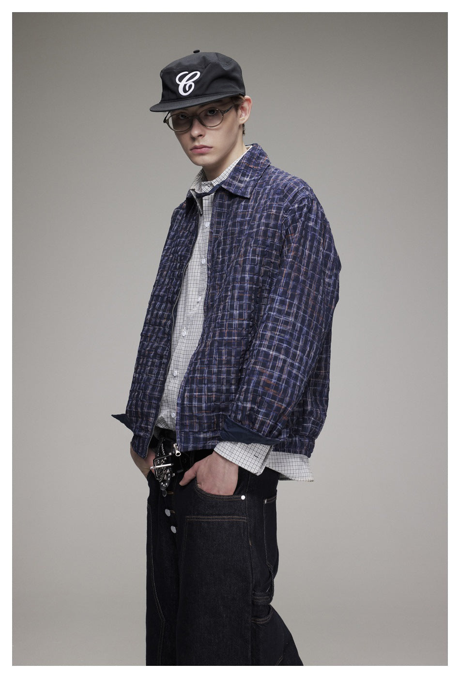 Three-quarter view of a model wearing an open navy plaid jacket over a light checked shirt.