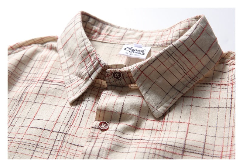 Close-up of the beige plaid shirt's pointed collar, button placket, and sewn-in neck label.