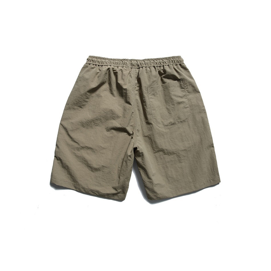 Back view of taupe shorts laid flat, with an elastic waistband and a single rear patch pocket.