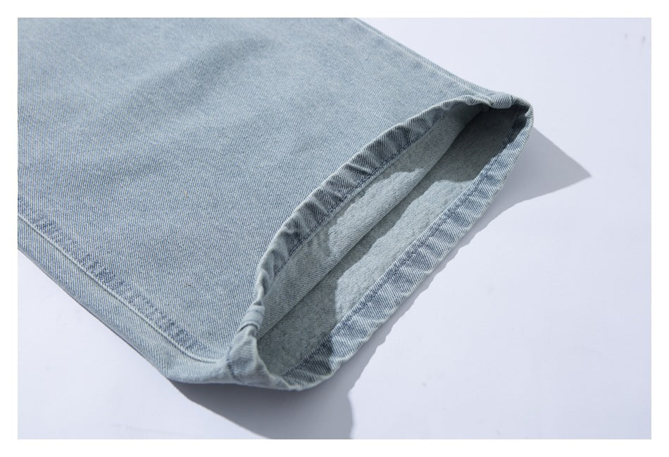 Close-up of a turned-up hem on light-wash blue denim, showing the stitched edge and inside.