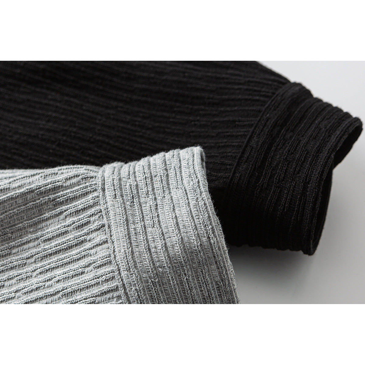 Close-up of ribbed jacket sleeves and cuffs in light gray and black.