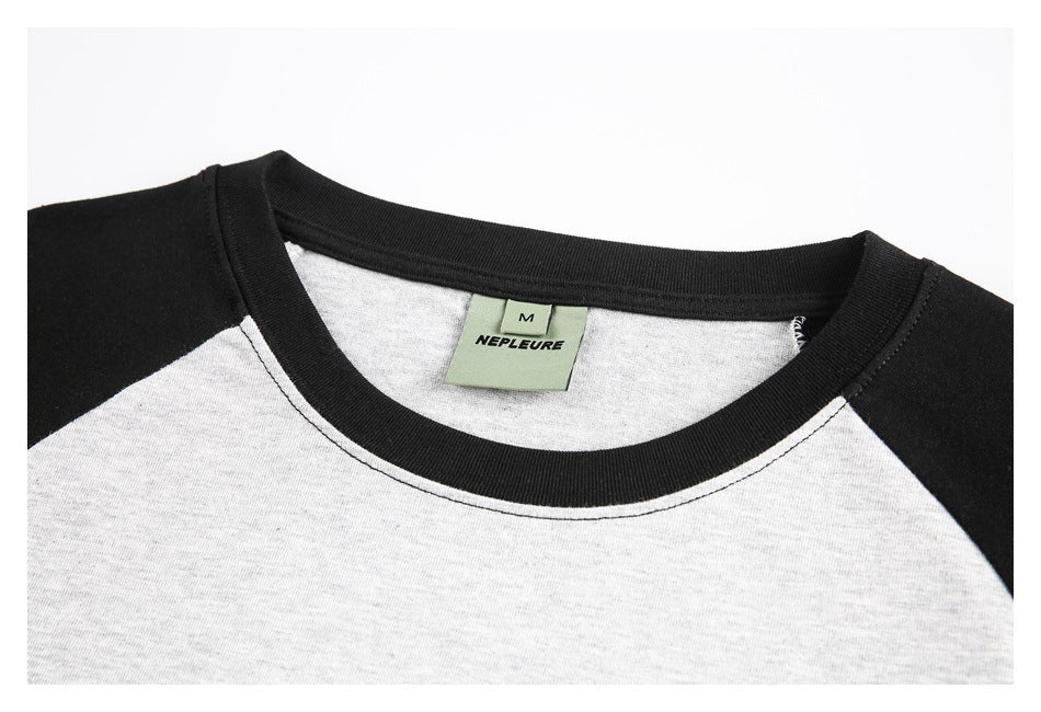 Close-up of a heather-gray raglan shirt neckline with black ribbed trim and a visible sewn neck label.