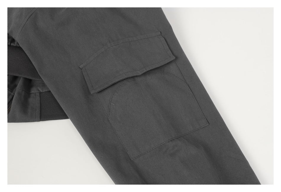 Close-up of a charcoal jacket sleeve with a rectangular flap pocket and lower patch pocket.
