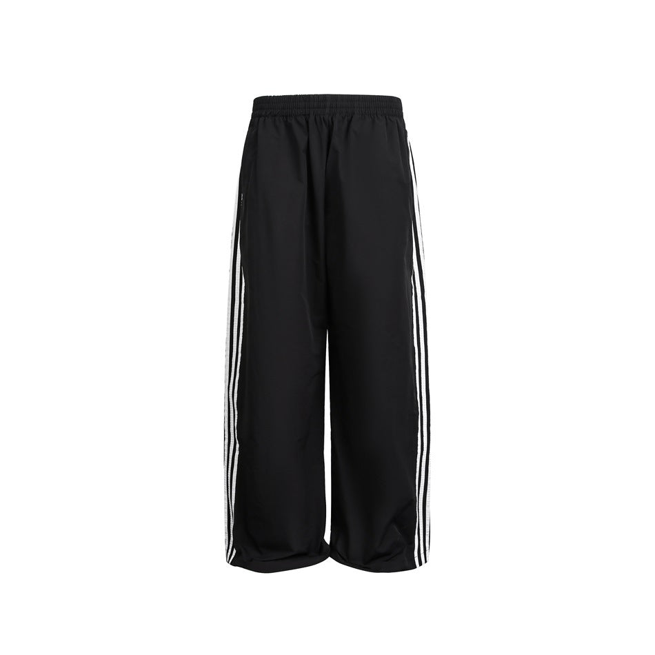 Front view of black wide-leg pants with an elastic waist and three white stripes down each outer leg.