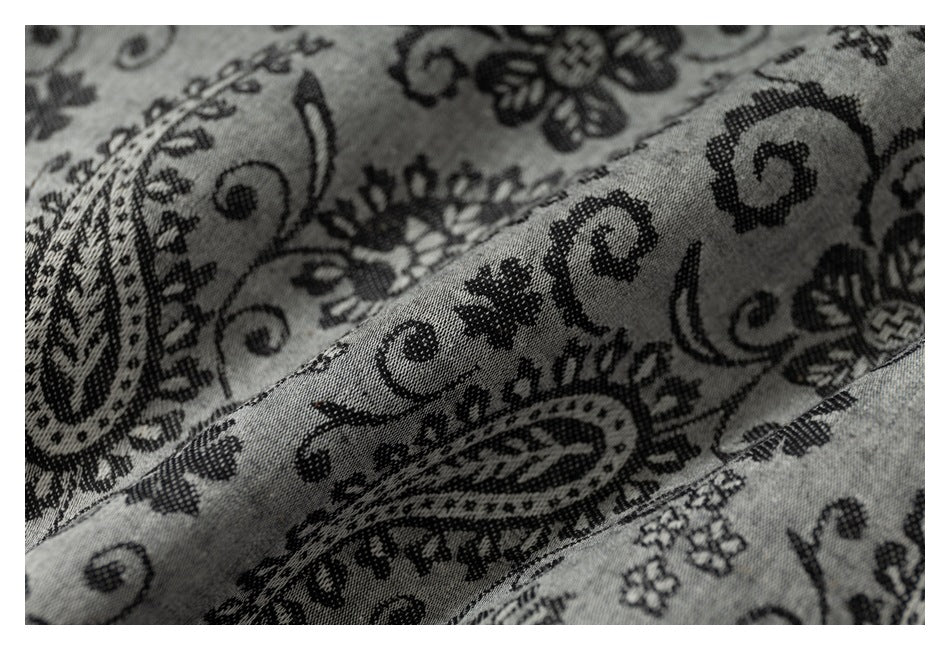 Close-up showing the texture and stitched seam of gray fabric with a black floral and paisley print.