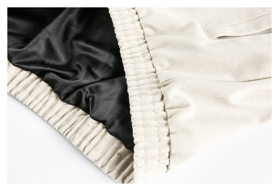 Close-up of the cream garment's gathered waistband, black inner lining, and pocket opening.