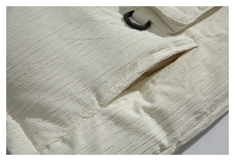 Close-up of an ivory jacket's textured fabric and angled pocket opening.