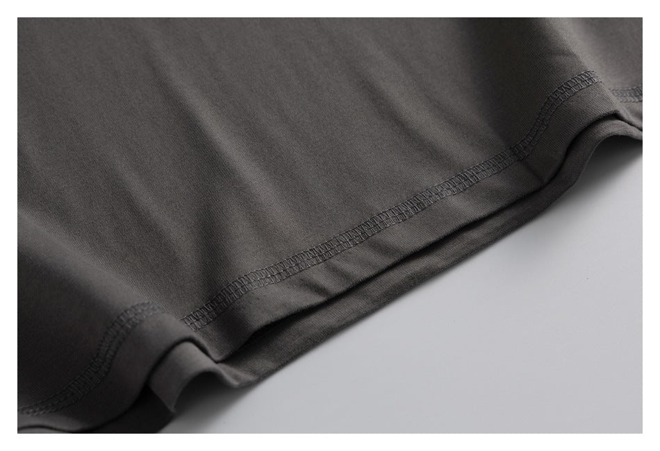 Close-up of the dark charcoal garment's hem seam and stitching against a light background.