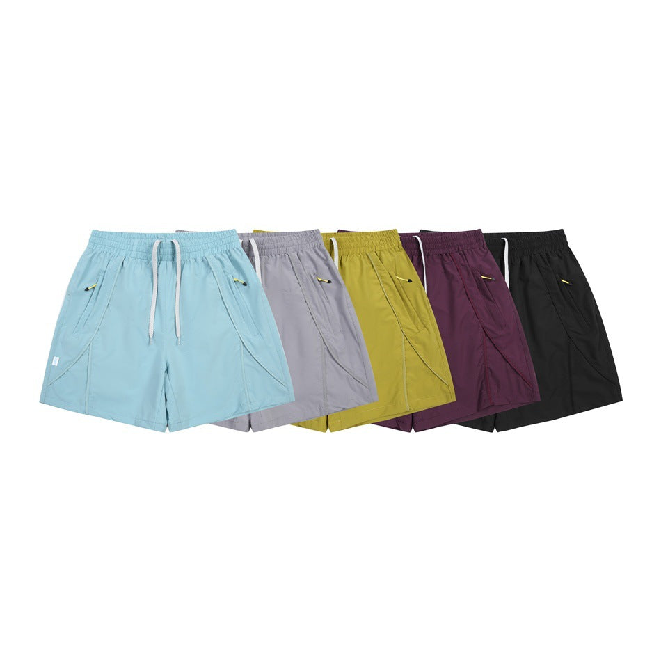 Five pairs of athletic shorts arranged together in light blue, gray, yellow, plum, and black.