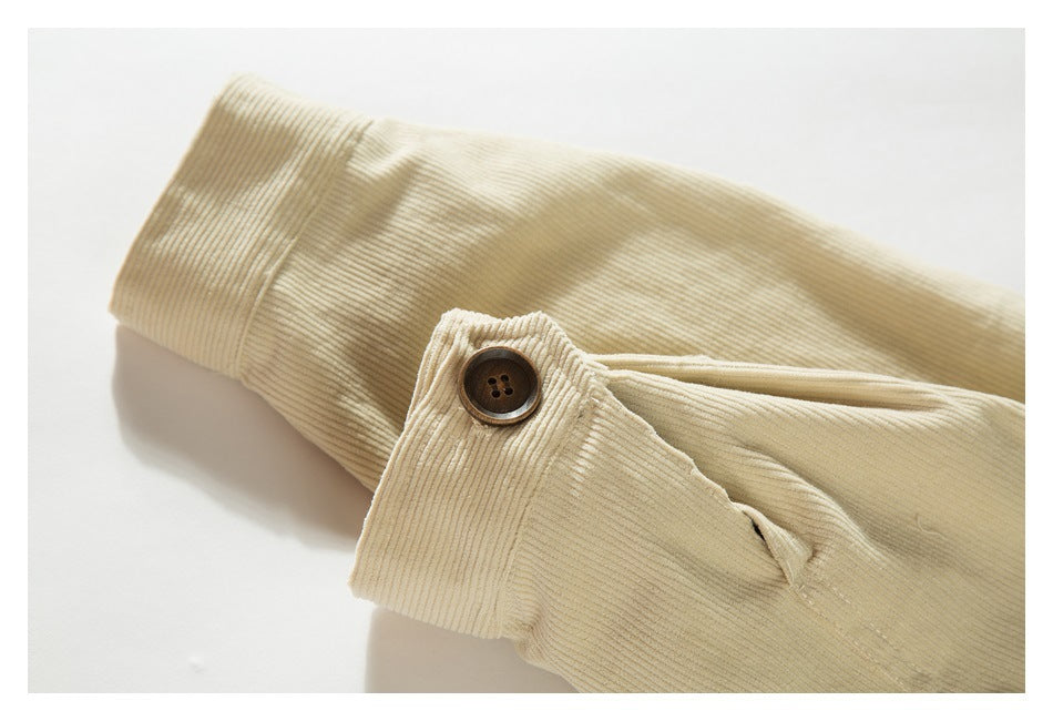 Close-up of a cream ribbed jacket sleeve cuff with a brown button and buttonhole.