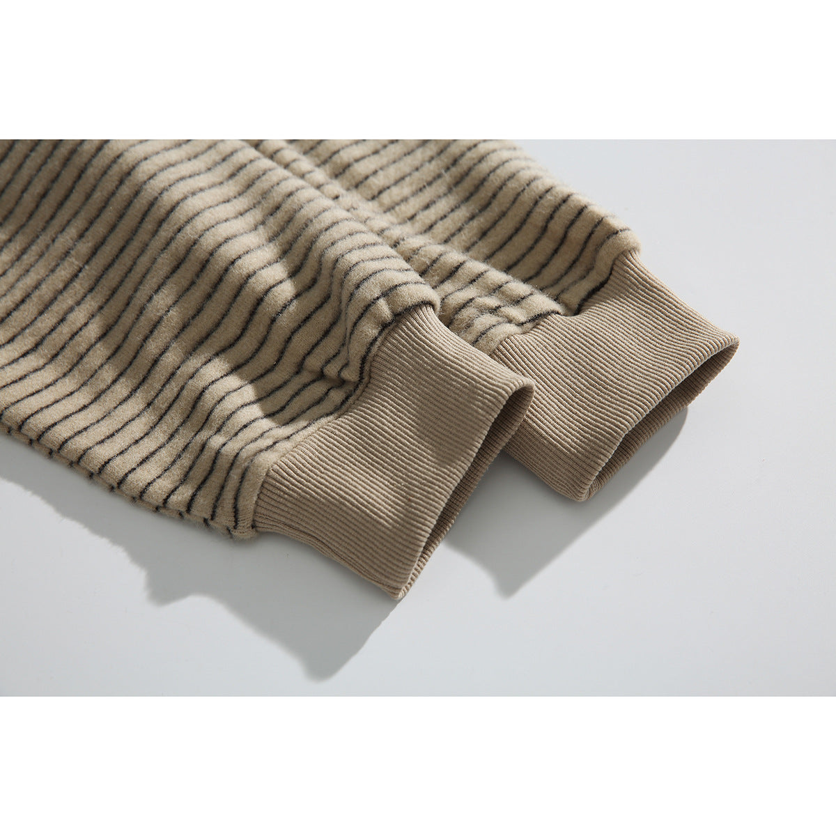 Close-up of the beige pinstriped hoodie’s ribbed cuffs and striped sleeves.