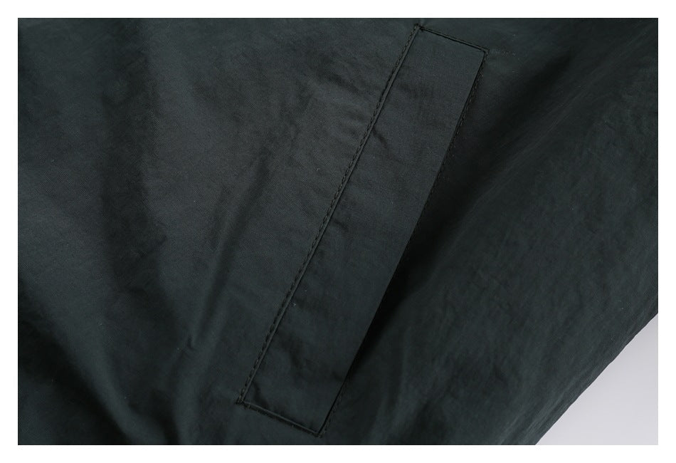 Close-up of a long rectangular stitched panel on dark jacket fabric.