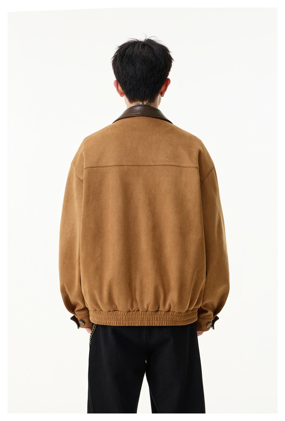 Closer back view of a model wearing a camel-brown jacket with a dark brown collar and gathered hem.