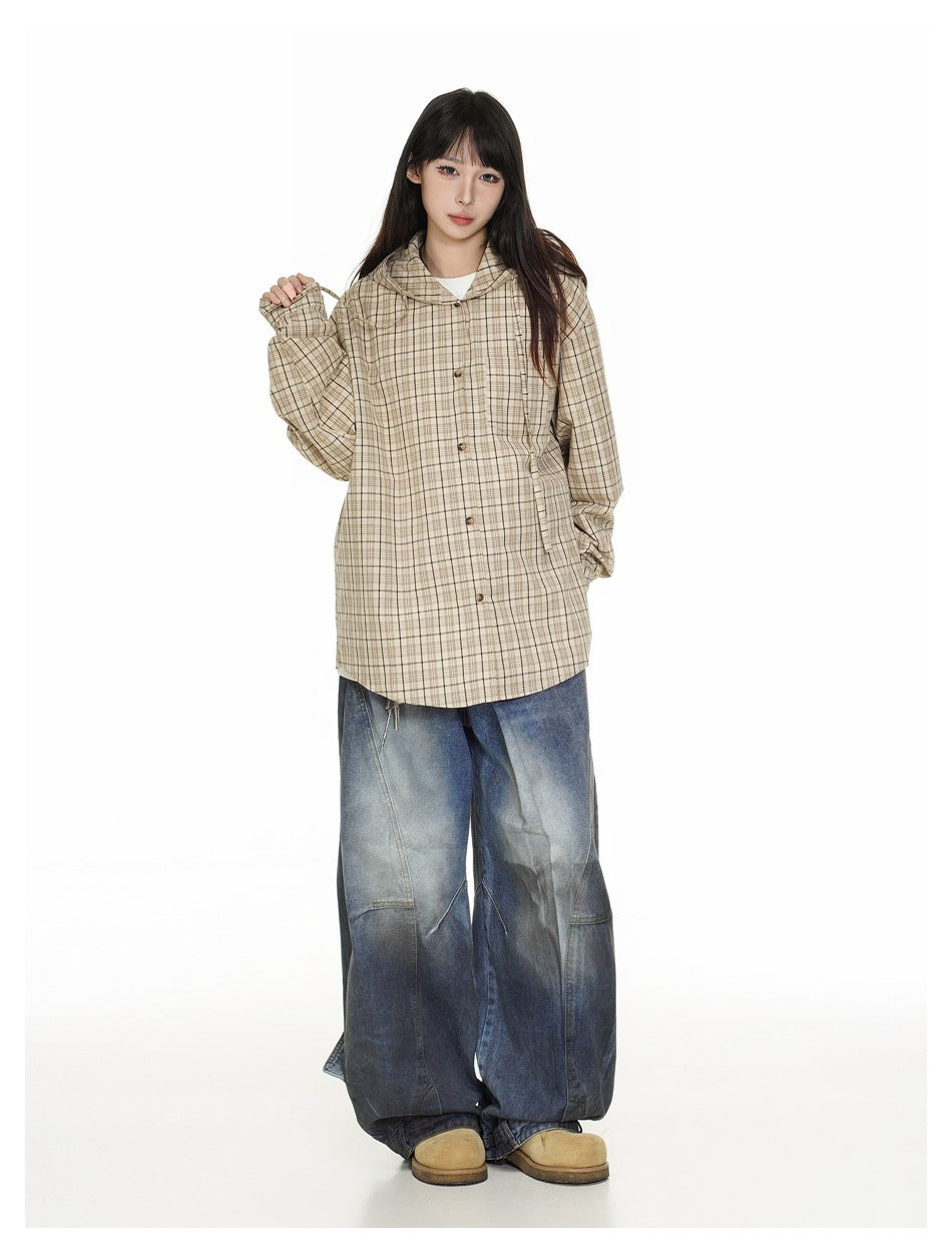 Full-length front view of a model wearing a beige plaid hooded shirt jacket and oversized blue jeans.