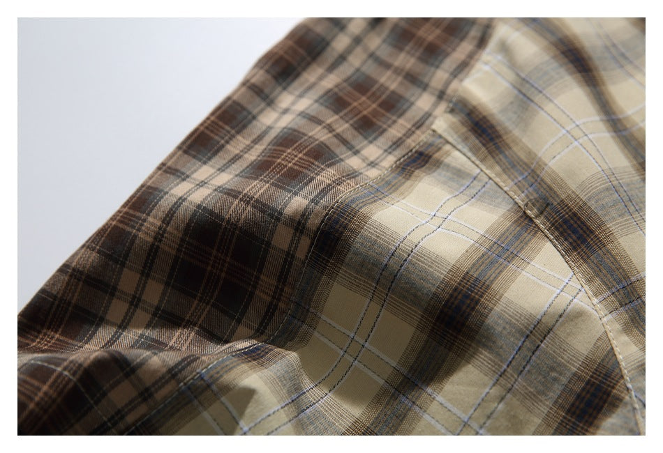 Close-up of a beige and brown plaid shirt, showing the intersecting checks and stitched seam.