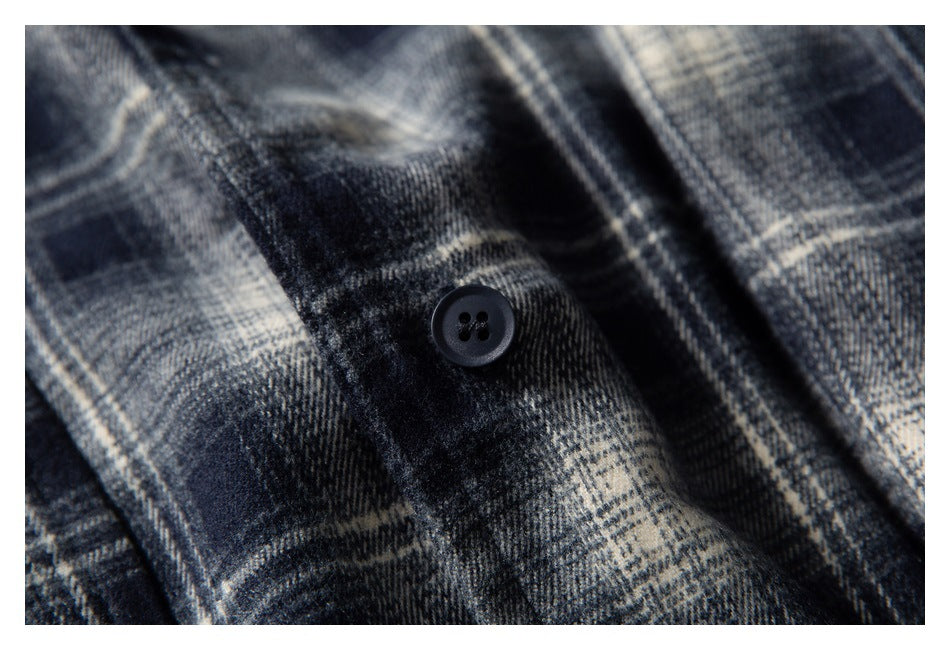 Macro view of a black button on navy, gray, and cream plaid fabric.