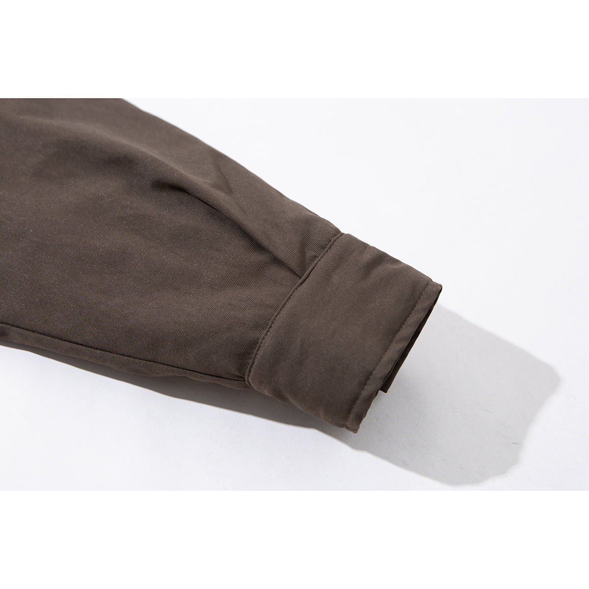 Close-up of a dark brown jacket sleeve ending in a wide buttonless cuff.