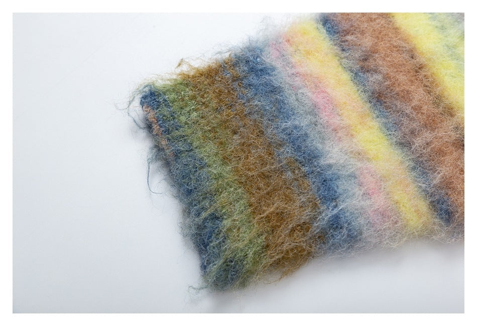 Close-up of fuzzy knit fabric with muted blue, olive, brown, pink, and yellow stripes.