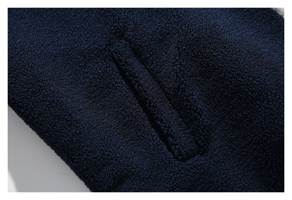 Close-up of a dark navy fleece jacket showing a narrow stitched pocket opening.