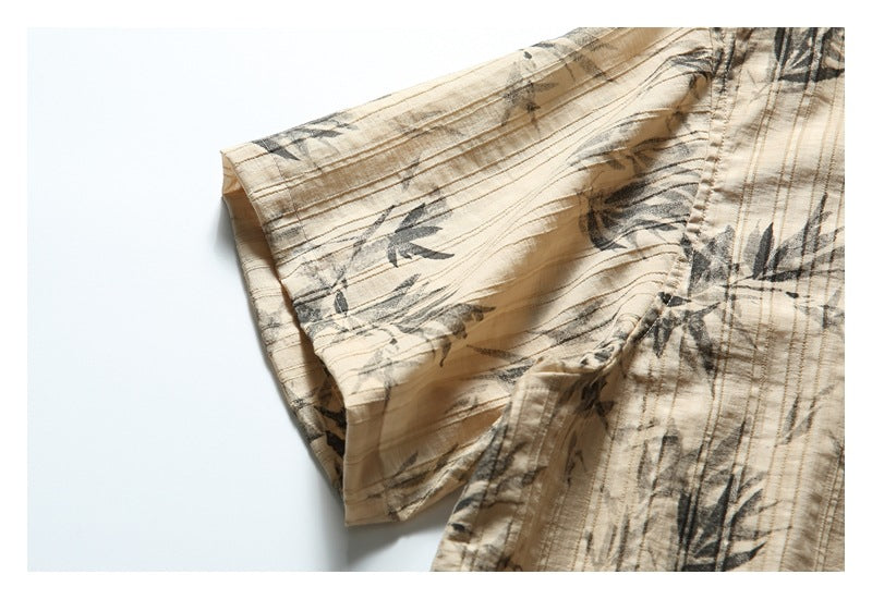 Close-up of the short sleeve and seam on tan fabric with a dark botanical print.