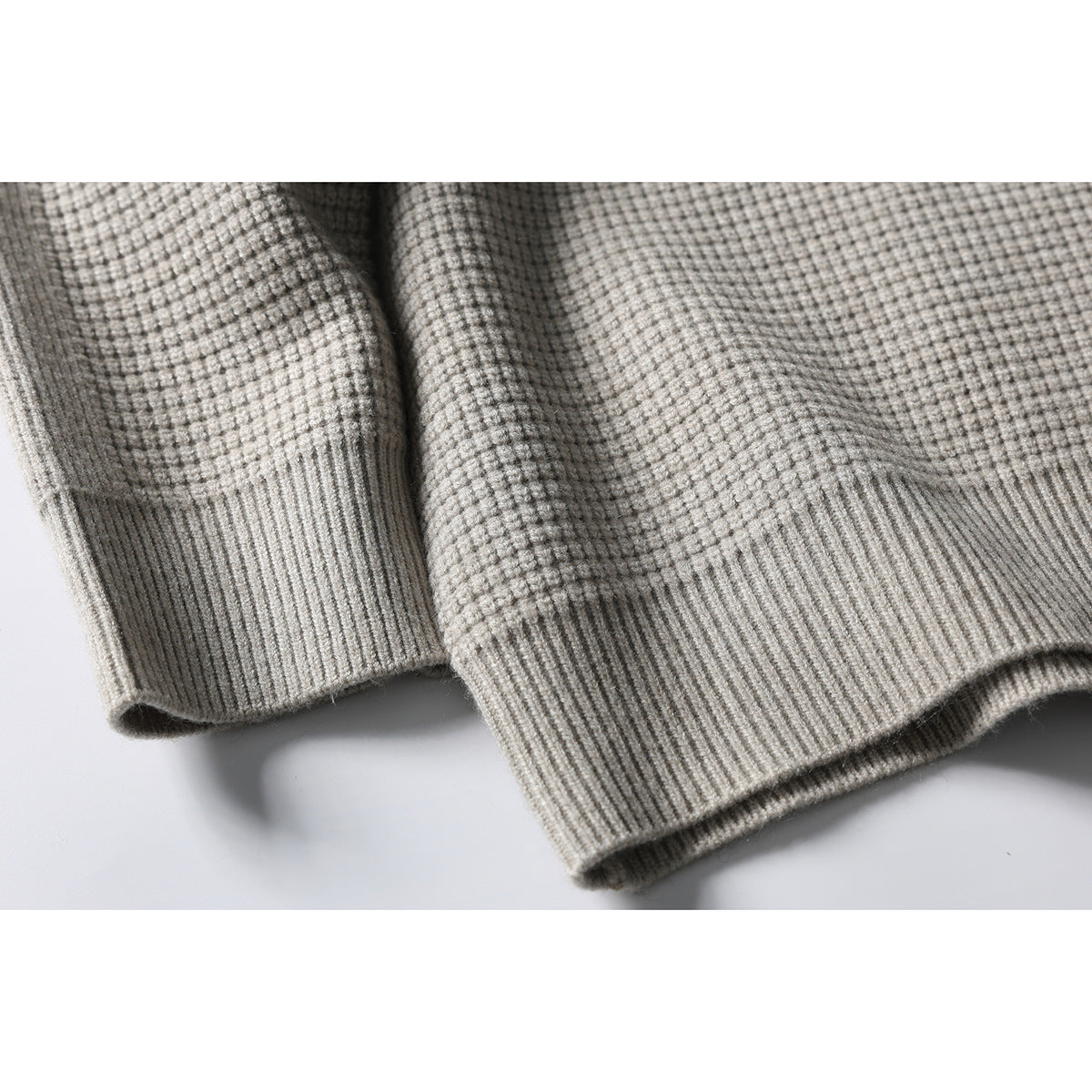 Close-up of the light gray cardigan's textured knit and ribbed cuffs and hem.