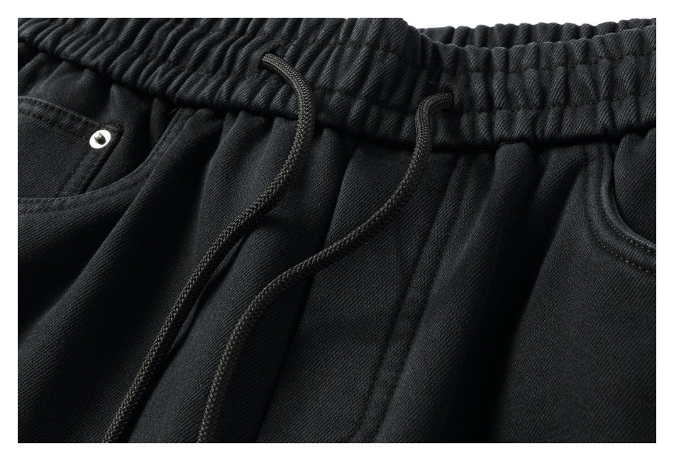 Close-up of black pants with an elastic drawstring waistband and front pockets.