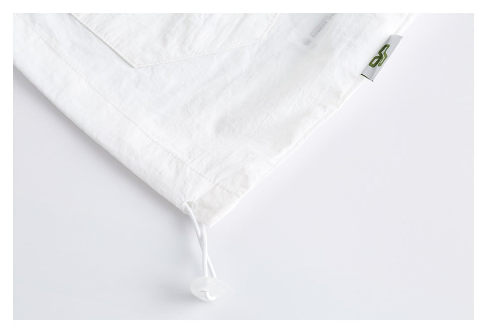 White garment hem with an adjustable drawcord and a small green logo tab.