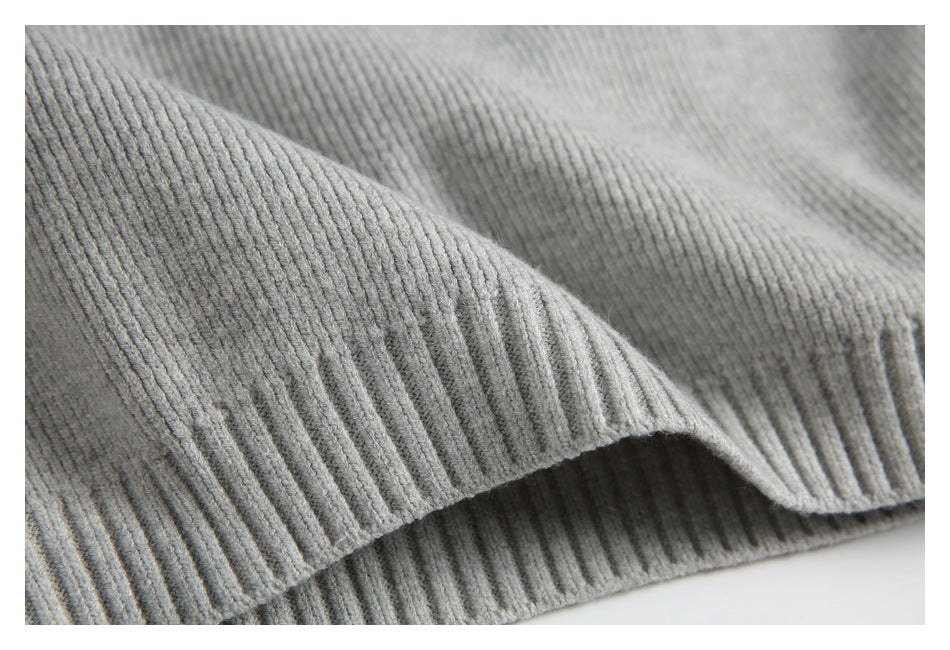 Close-up of a folded ribbed edge and knit texture on a light gray garment.