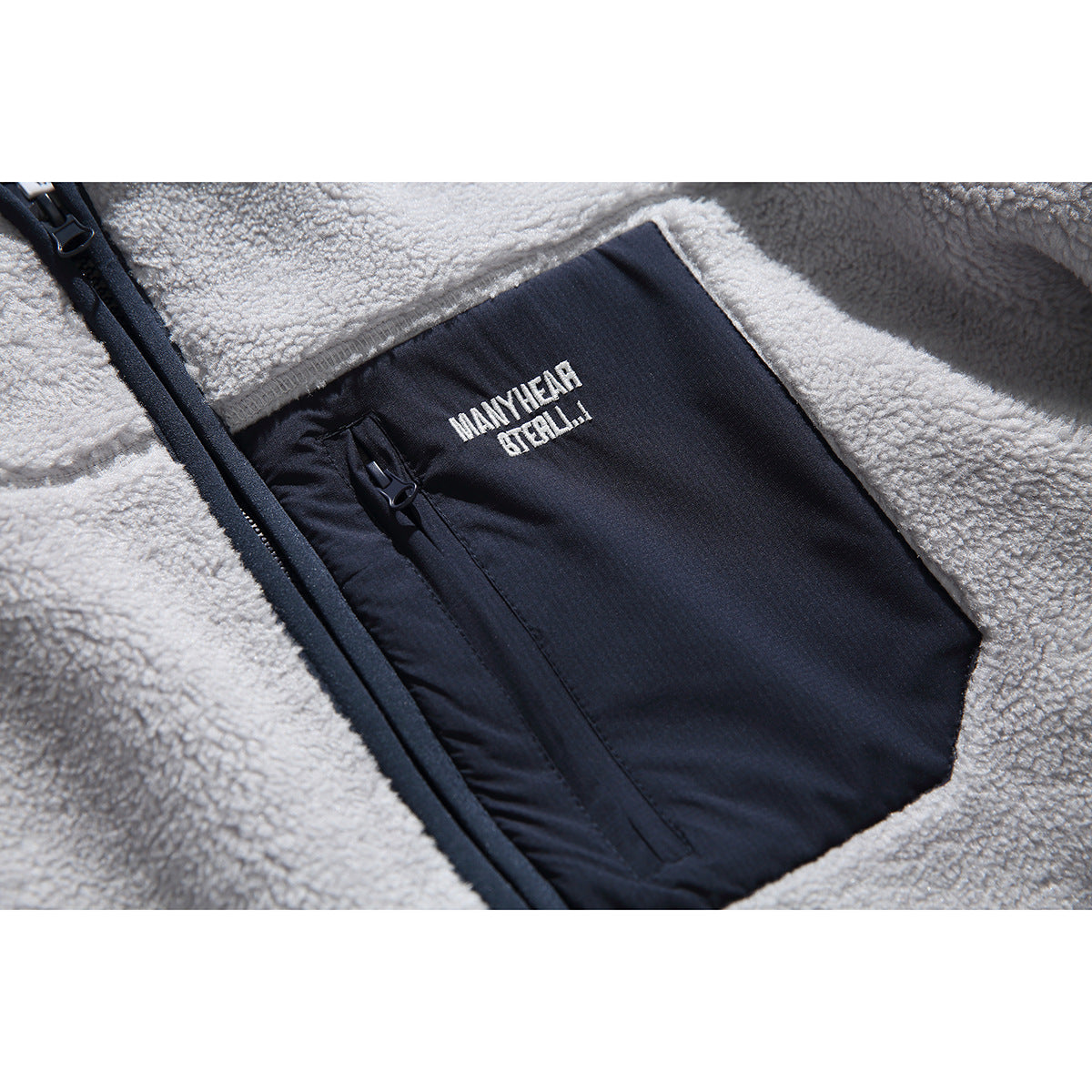 Close-up of the jacket's navy zip chest pocket, white lettering, and gray fleece panels.
