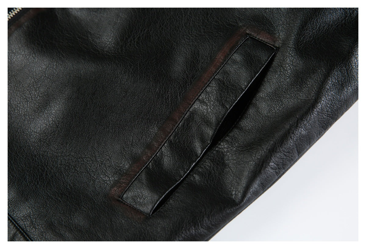Close-up of a black leather-look jacket showing a narrow welt pocket and pebbled surface.